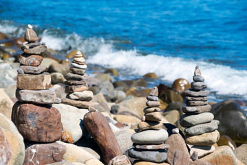 Fototapeta na wymiar Pyramids of stones on the beach with the bright sun. Crimea.
