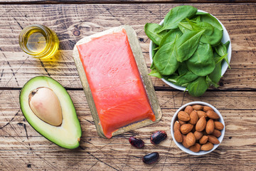 Concept Healthy food antioxidant products: fish and avocado, nuts and fish oil, grapefruit on wooden background.