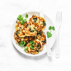 Potato latkes with spinach and herbs on a light background, top view. Delicious breakfast or snack
