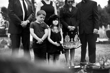 Sad grandkids standing by the grave