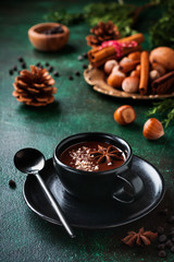Hot chocolate with anise and nuts in black ceramic cup on old dark green concrete background. Selective focus.