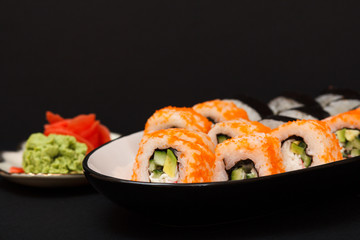 Uramaki California. Sushi rolls, plate with red pickled ginger and wasabi.