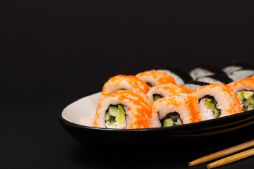 Uramaki California. Sushi rolls on a plate with wooden sticks.