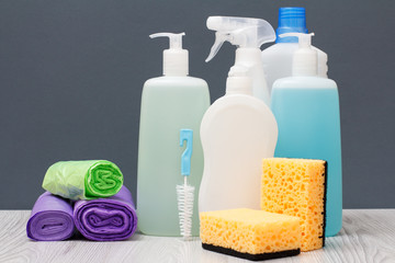 Bottles of detergent and sponges on gray background.