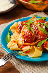 Italian pasta pappardelle with meatballs in tomato sauce.