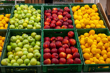 A large rack with baskets with different types of apples and lemons in the fruit department of the...