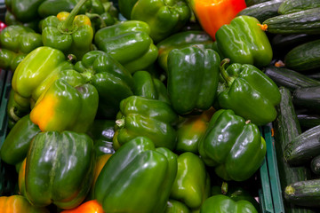 Fototapeta na wymiar Close-up on a large number of bright green peppers from a fresh crop ready for sale lying on the counter in the vegetable department of the shopping center