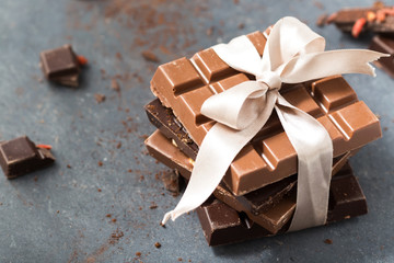 Chocolate bars with white bow on a grey background