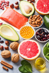 Healthy food antioxidant products: fish and avocado, nuts and fish oil, grapefruit spinach and oil on a gray concrete background.