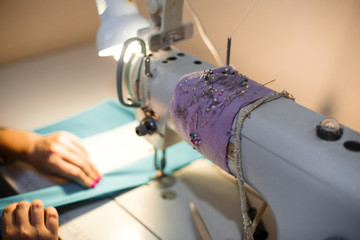 Workplace seamstress. Tailoring industry. Girl sews on the sewing machine. Factory clothing