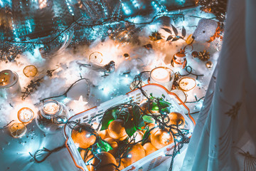 Artificial snow with garland, candles and a box of oranges on the windowsill