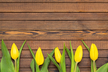 Beautiful yellow tulips on wooden background. Top view, copy space. Holidays concept. Add text