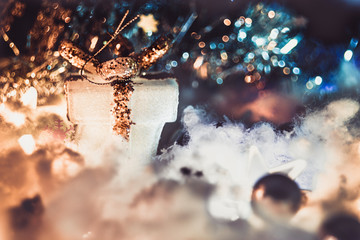 White gift with gold sequins and artificial snow on dark blurred background