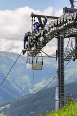 Two workers doing maintenance on cable car with Alps mountains in backgroun, Schonleitenbahn on Wildenkarkogel, Saalbach-Hinterglemm, Zell am See district, Salzburg federal state, Austria
