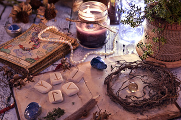 Old tarot cards deck, runes and dried roots with book on table. Magic gothic ritual. Wicca, esoteric and occult background