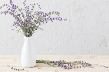 lavender in white vase on wooden table