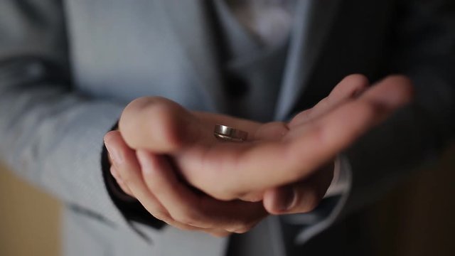 groom holds wedding rings in hands