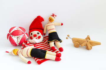 Front view of funny vintage children toys on white background. Assortment consists of a clown, a male doll, a female doll, a ball and a wooden grasshopper.