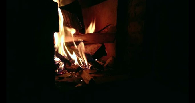 Firewood burns in a firebox at night