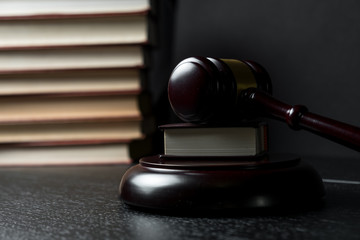 Judge gavel beside pile of books on wooden background