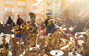 Various antique jars, jugs, pitchers at flea market with blurred customers and sellers in...