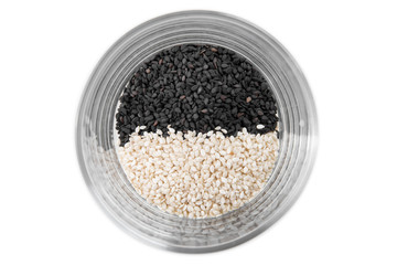 Obraz na płótnie Canvas Black and white sesame seeds in a glass cup on a white background, top view