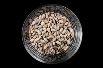 Sunflower seeds in a glass beaker on a black background, top view