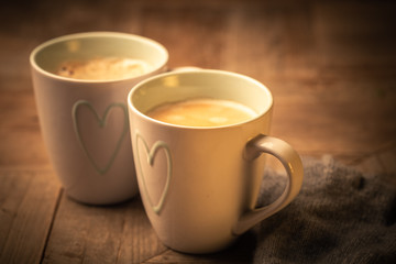 Two mugs of hot steaming frothy coffee