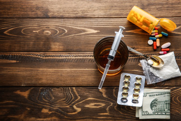 Drugs and alcohol on wooden background. Concept of addiction