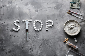 Word STOP made of drugs and syringe on grey background. Concept of addiction