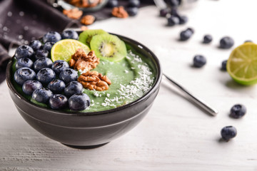 Bowl with tasty spirulina smoothie on white wooden table