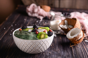 Bowl with tasty spirulina smoothie on dark wooden table