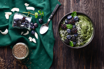 Tasty spirulina smoothie with berries in bowl on dark wooden table