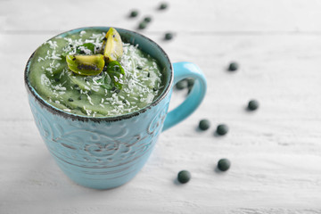 Cup with tasty spirulina smoothie on white wooden table