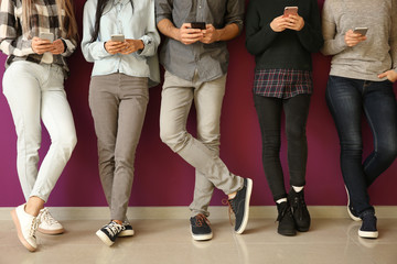 Young people using mobile phones near color wall. Concept of addiction