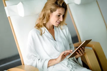 Zelfklevend Fotobehang Badkamer Beautiful woman relaxing and using tablet in spa  © NDABCREATIVITY