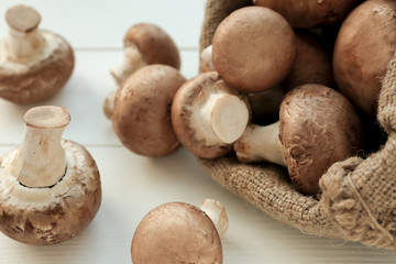 Bag with fresh mushrooms on white wooden table