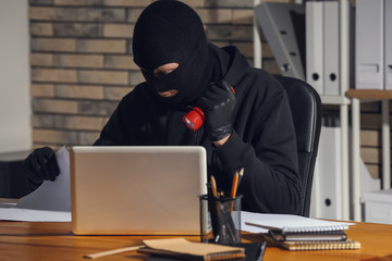 Male thief with flashlight  searching for documents in office