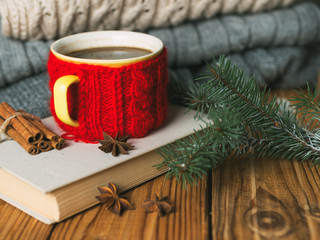 Mug of hot coffee with a warm knitted sweater and a book