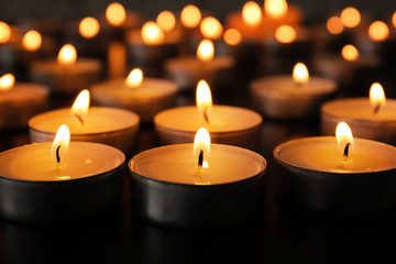 Burning candles on dark table, closeup