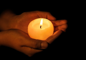 Woman holding burning candle on dark background