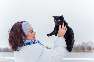 Plus size elegant woman at winter day in park walking outdoor with her cat, cat lover lady  lifestyle, magic cold Christmas time with pet, Pets life