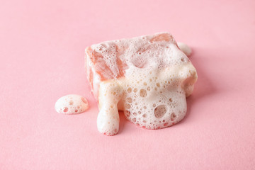 Handmade soap bar with foam on color background