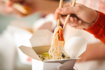 Woman eating chinese noodles from takeaway box, closeup