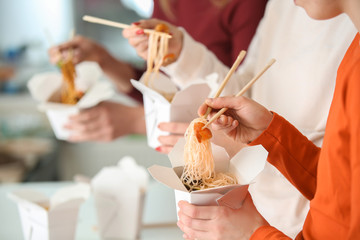 People eating chinese noodles from takeaway boxes, closeup