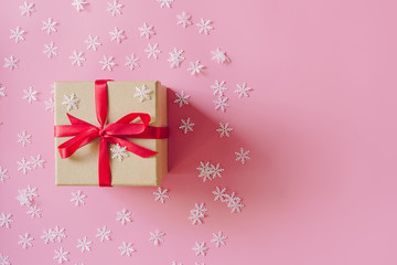Brown gift box on the pink background with christmas decoration. Minimal styled holiday card with copy space.