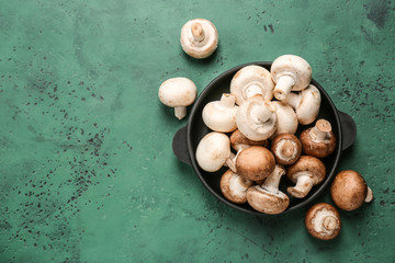 Pan with fresh mushrooms on color table