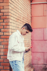Man texting on phone. Outdoor portrait of modern young guy with mobile in the street