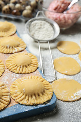 Board with raw ravioli on kitchen table, closeup
