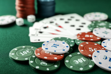 Chips with cards for poker game on green table in casino